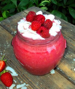Raspberry Coconut Protein Mousse in a glass jar with frozen raspberries and coconut on a top-energy